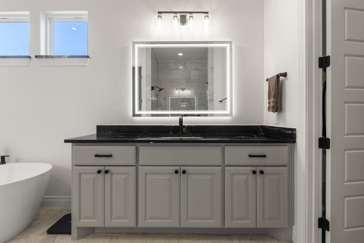 Primary vanity with backlit mirror and soapstone counter